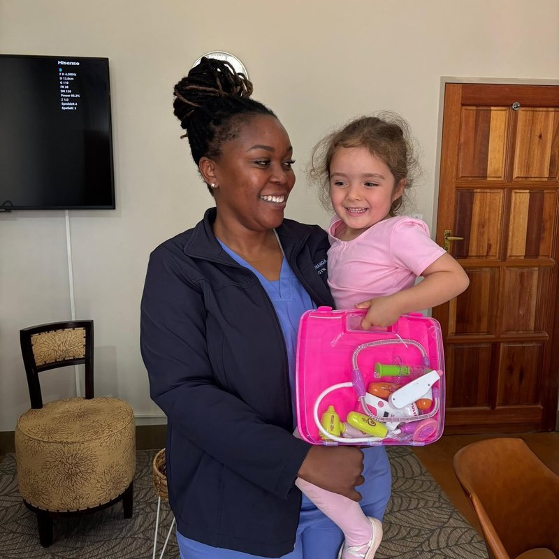 Staff member with a young child holding a toy medical kit